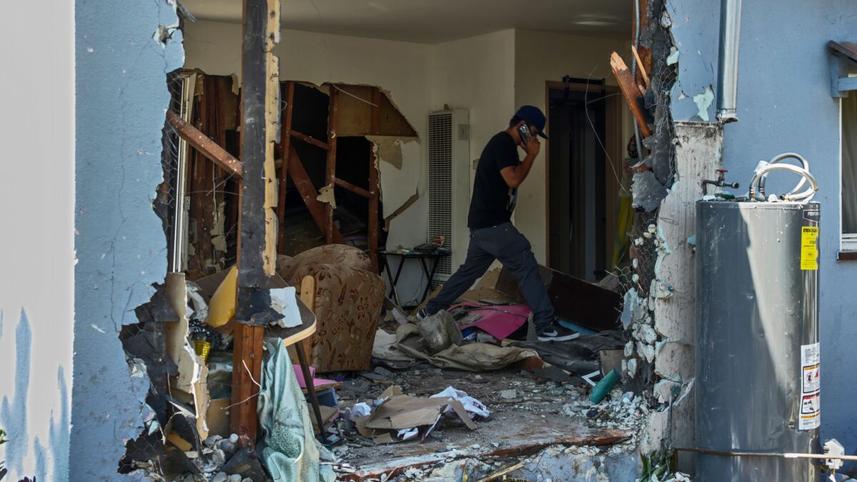A family member visits the house where one person was killed and 11 others were injured Wednesday night when police say a driver crashed her car into the Harbor Gateway home where a prayer group was meeting.
