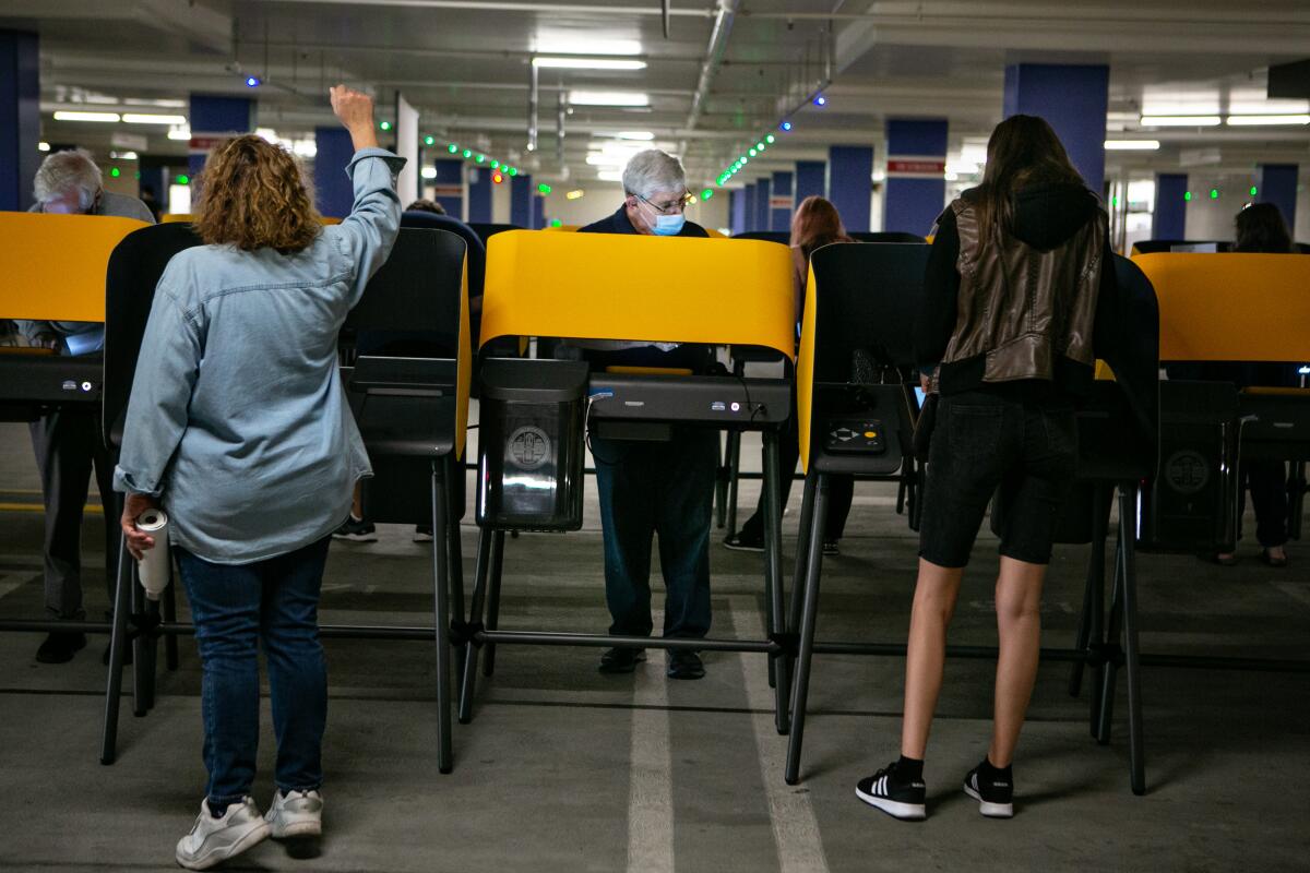 A poll worker holds her arm in the air directing a voter.