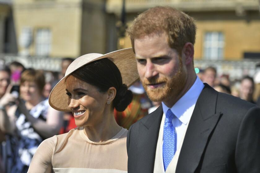 Meghan, the Duchess of Sussex walks with her husband, Prince Harry as they attend a garden party at Buckingham Palace in London on May 22, 2018.