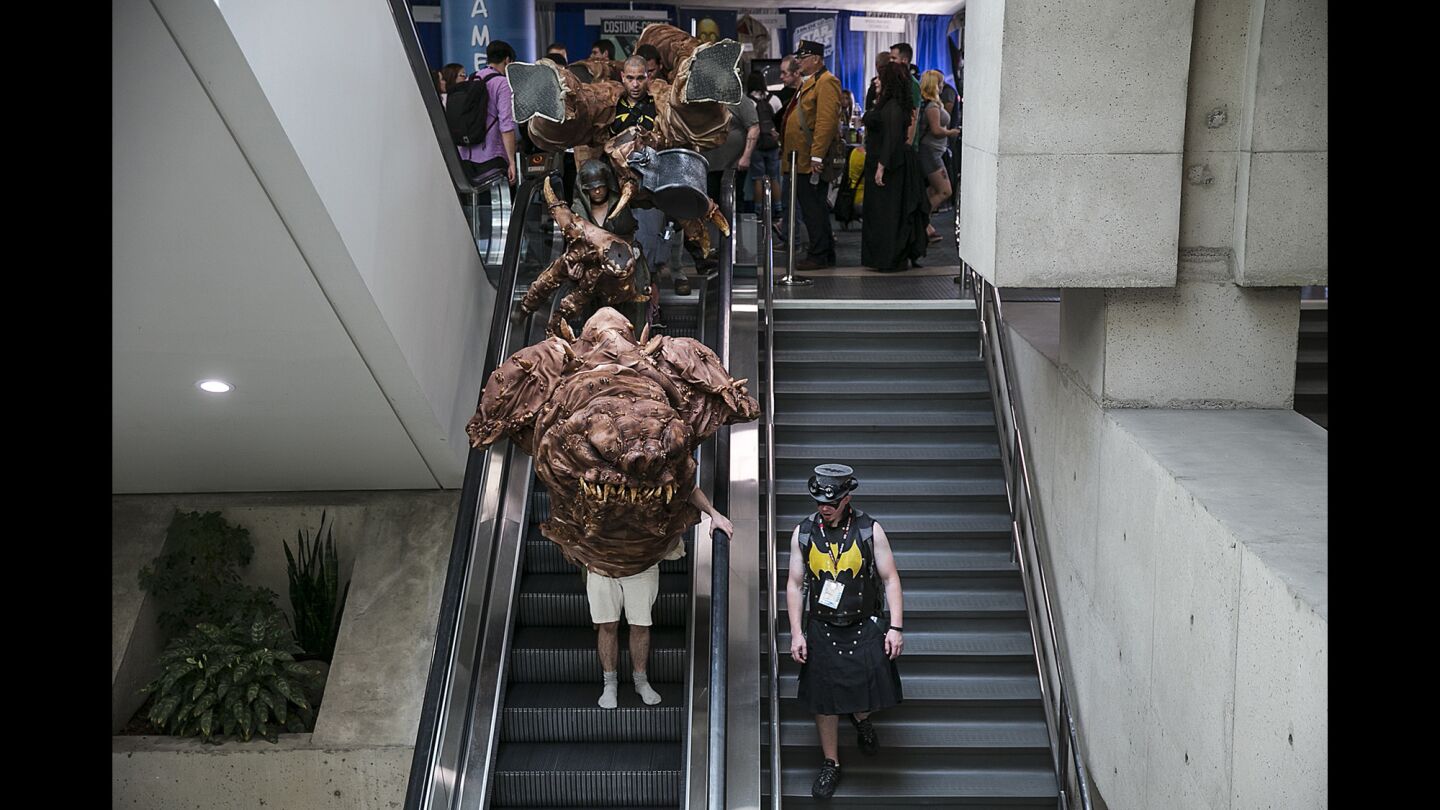 A cosplay Rancor from Star Wars descends an escalator in pieces as it makes an appearance at Comic-Con 2016.