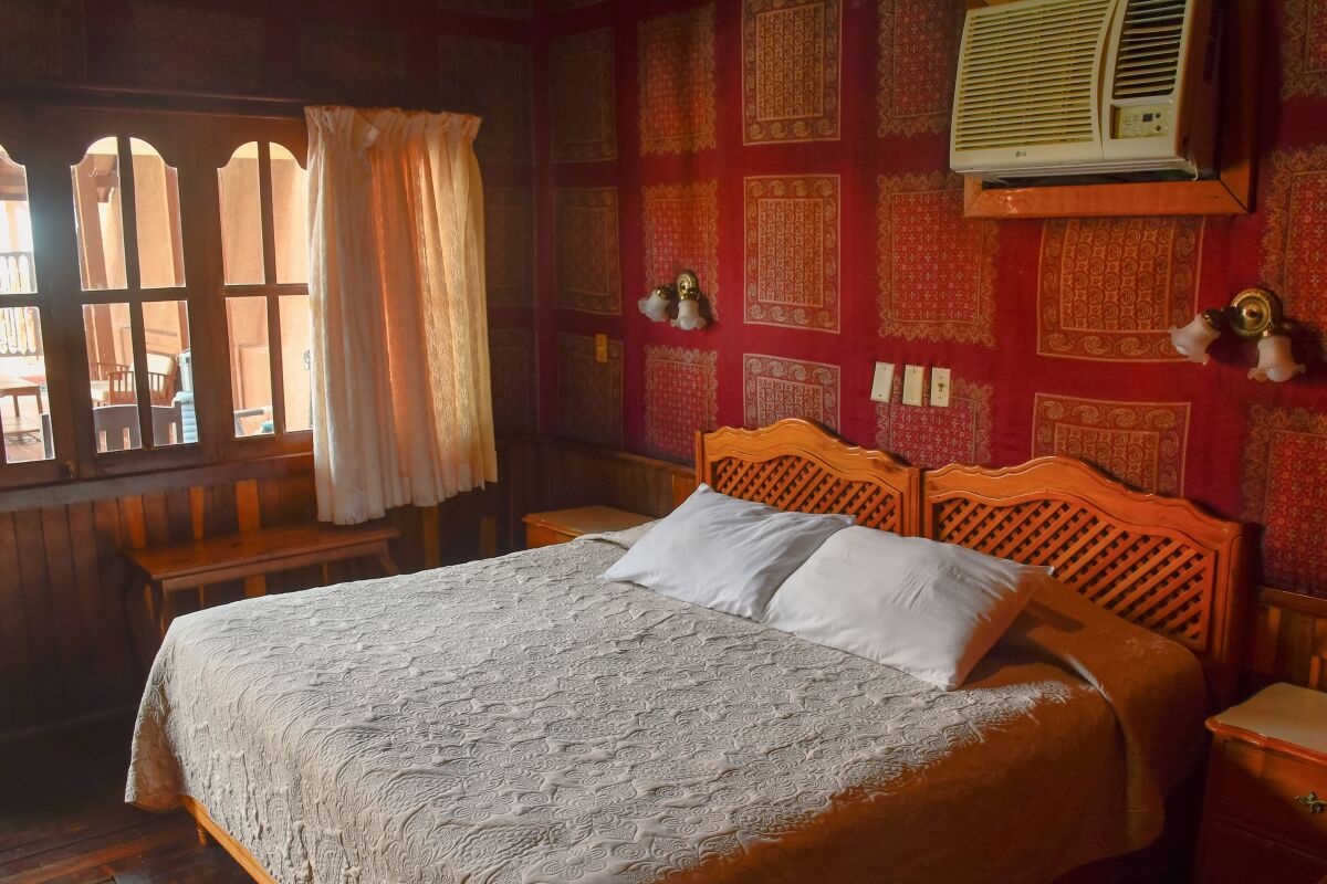 The inside of a room at Hotel Frances, showing a large bed and ornate red wallpaper.
