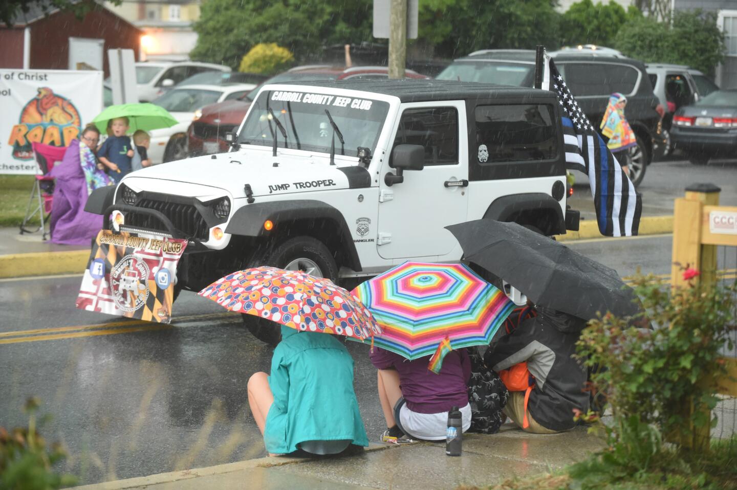 Spectators try to stay dry as they watch the parade from the safety of umbrellas during the Manchester Volunteer Fire Company carnvial on Tuesday, July 2.