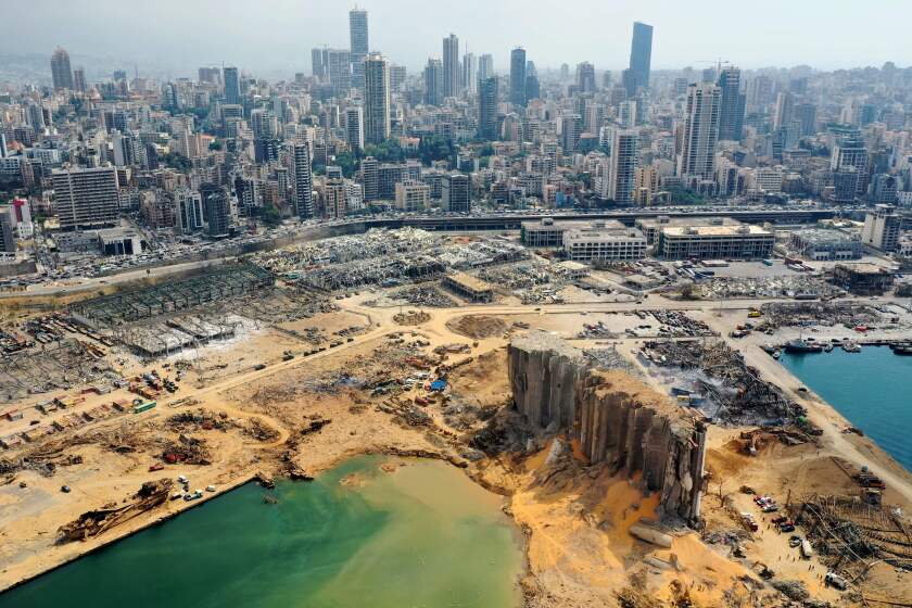 TOPSHOT - An aerial view taken on August 7, 2020, shows a partial view of the port of Beirut, the damaged grain silo and the crater caused by the colossal explosion three days earlier of a huge pile of ammonium nitrate that had languished for years in a port warehouse, leaving scores of people dead or injured and causing devastation in the Lebanese capital. The city of Beirut can be seen in the background. (Photo by - / AFP) (Photo by -/AFP via Getty Images)