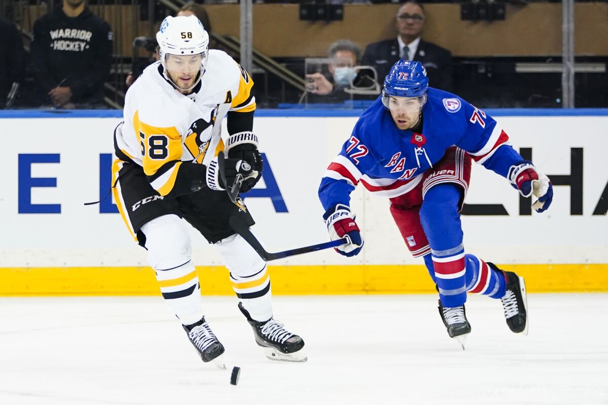 Pittsburgh Penguins' Kris Letang (58) fights for control of the puck with New York Rangers' Filip Chytil (72) during the first period of Game 5 of an NHL hockey Stanley Cup first-round playoff series Wednesday, May 11, 2022, in New York. (AP Photo/Frank Franklin II)