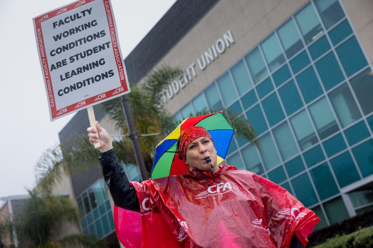 A woman wearing a red rain poncho holds a sign while picketing. 