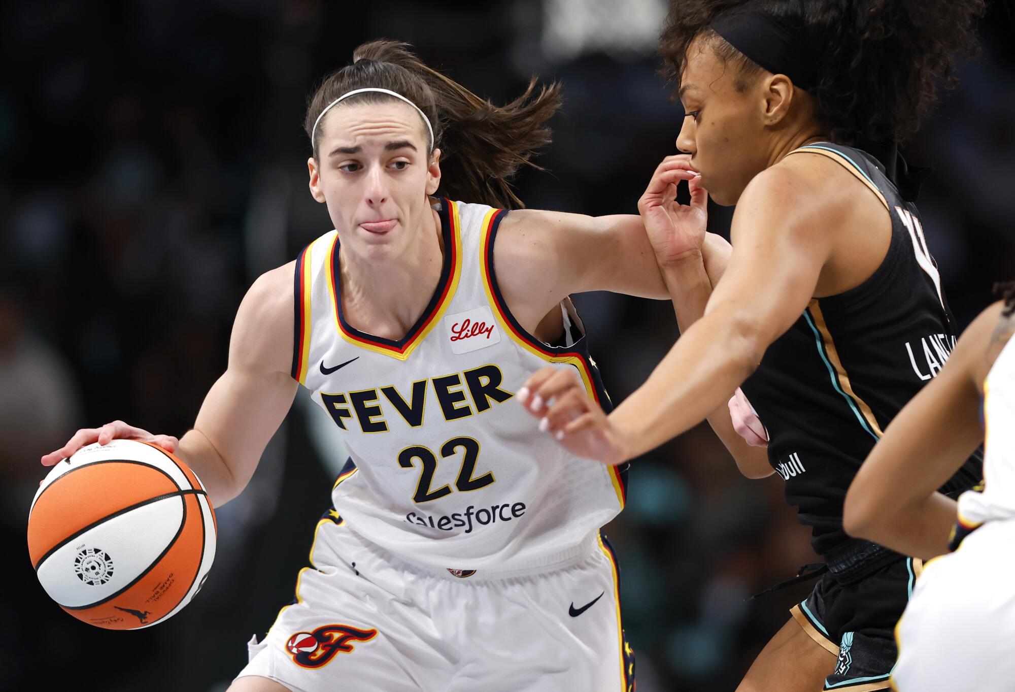 Indiana Fever guard Caitlin Clark drives to the basket under pressure from New York Liberty forward Betnijah Laney-Hamilton 