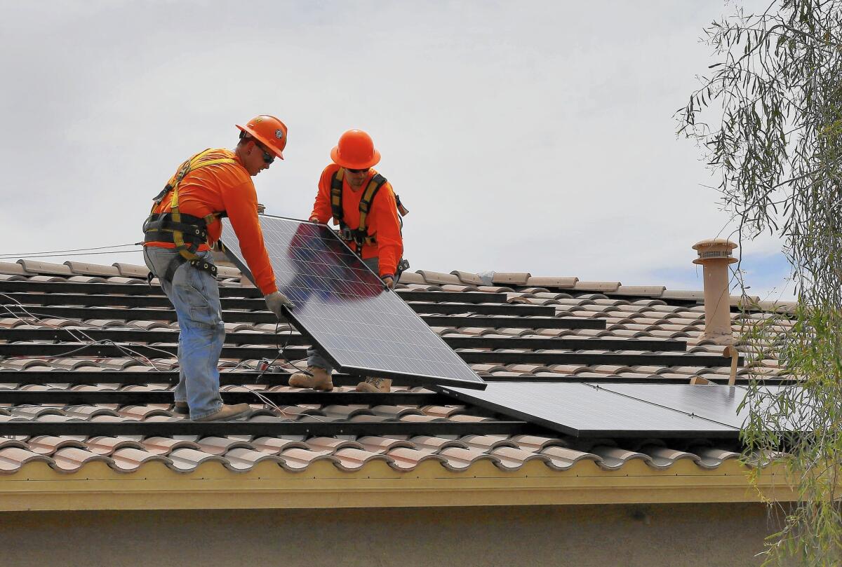 Electricians install solar panels on a roof for Arizona Public Service company in Goodyear, Ariz. in July of 2015.