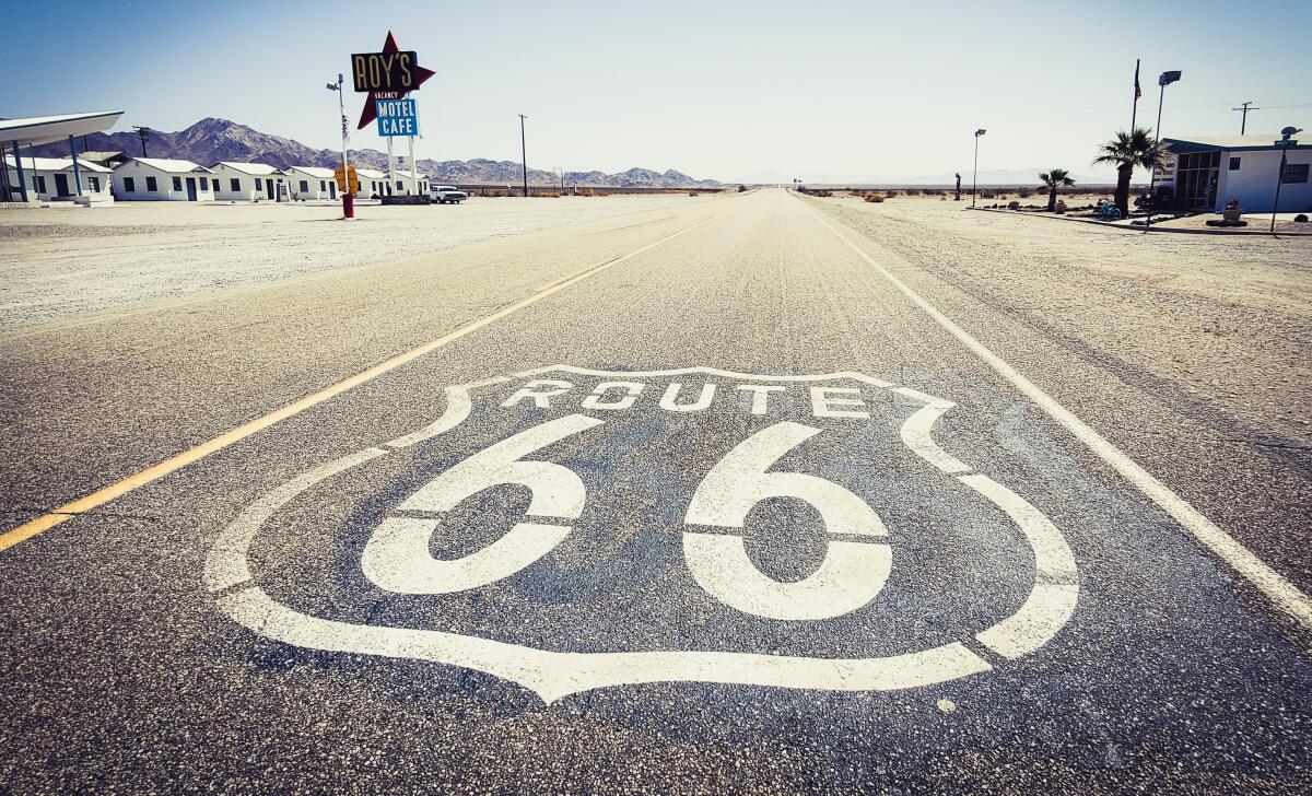 An empty stretch of desert road with the words "Route 66" painted on the blacktop