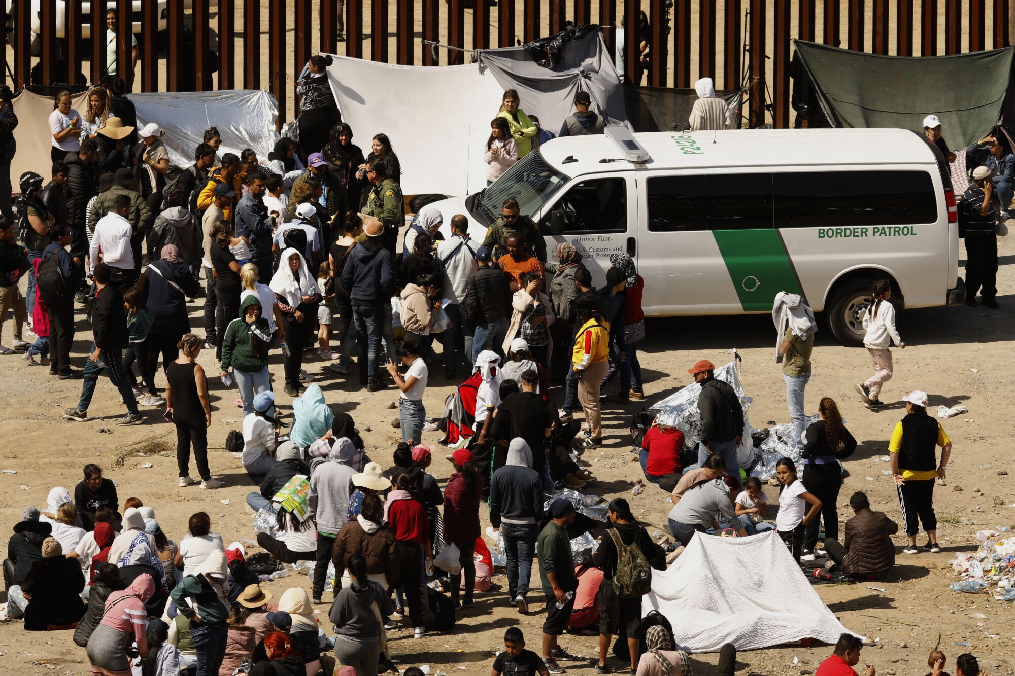 યુએસ સરહદ પેટ્રોલિંગ એજન્ટો તિજુઆના, મેક્સિકોથી યુનાઇટેડ સ્ટેટ્સમાં પ્રવેશવાની આશા રાખતા સ્થળાંતરકારો સાથે વાત કરે છે
