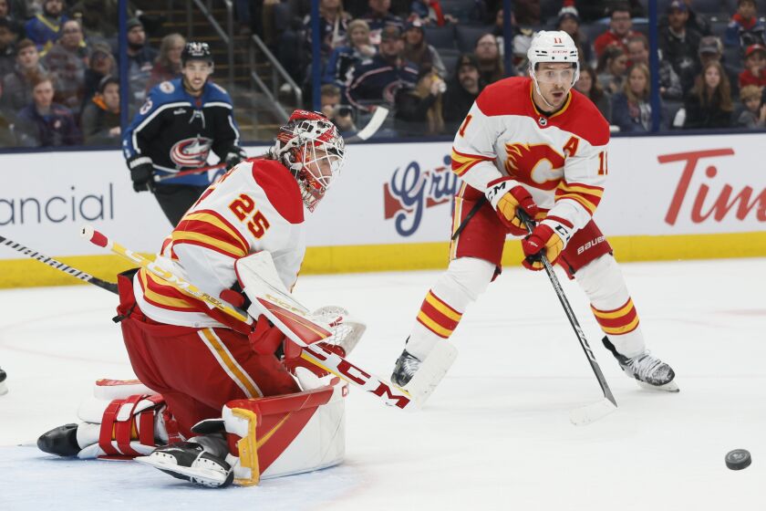 Calgary Flames' Jacob Markstrom, left, makes a save against the Columbus Blue Jackets during the second period of an NHL hockey game Friday, Dec. 9, 2022, in Columbus, Ohio. (AP Photo/Jay LaPrete)