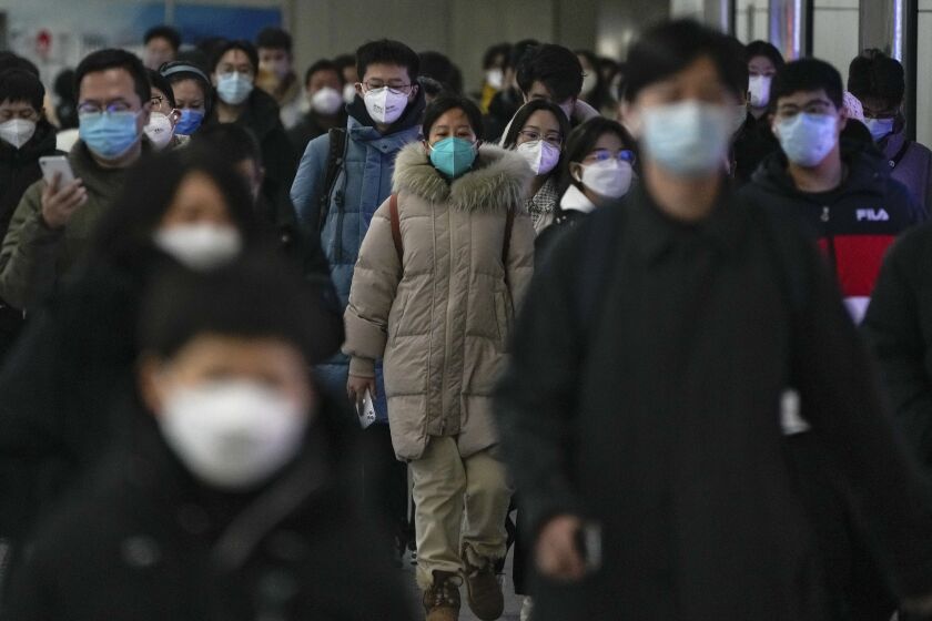 FILE - Masked commuters walk through a walkway in between two subway stations as they head to work during the morning rush hour in Beijing, Tuesday, Dec. 20, 2022. China continues to adapt to an easing of strict virus containment regulations. About three years ago, the original version of the coronavirus spread from China to the rest of the world and was eventually replaced by the delta variant, then omicron and its descendants, which continue plaguing the world today. (AP Photo/Andy Wong, File)