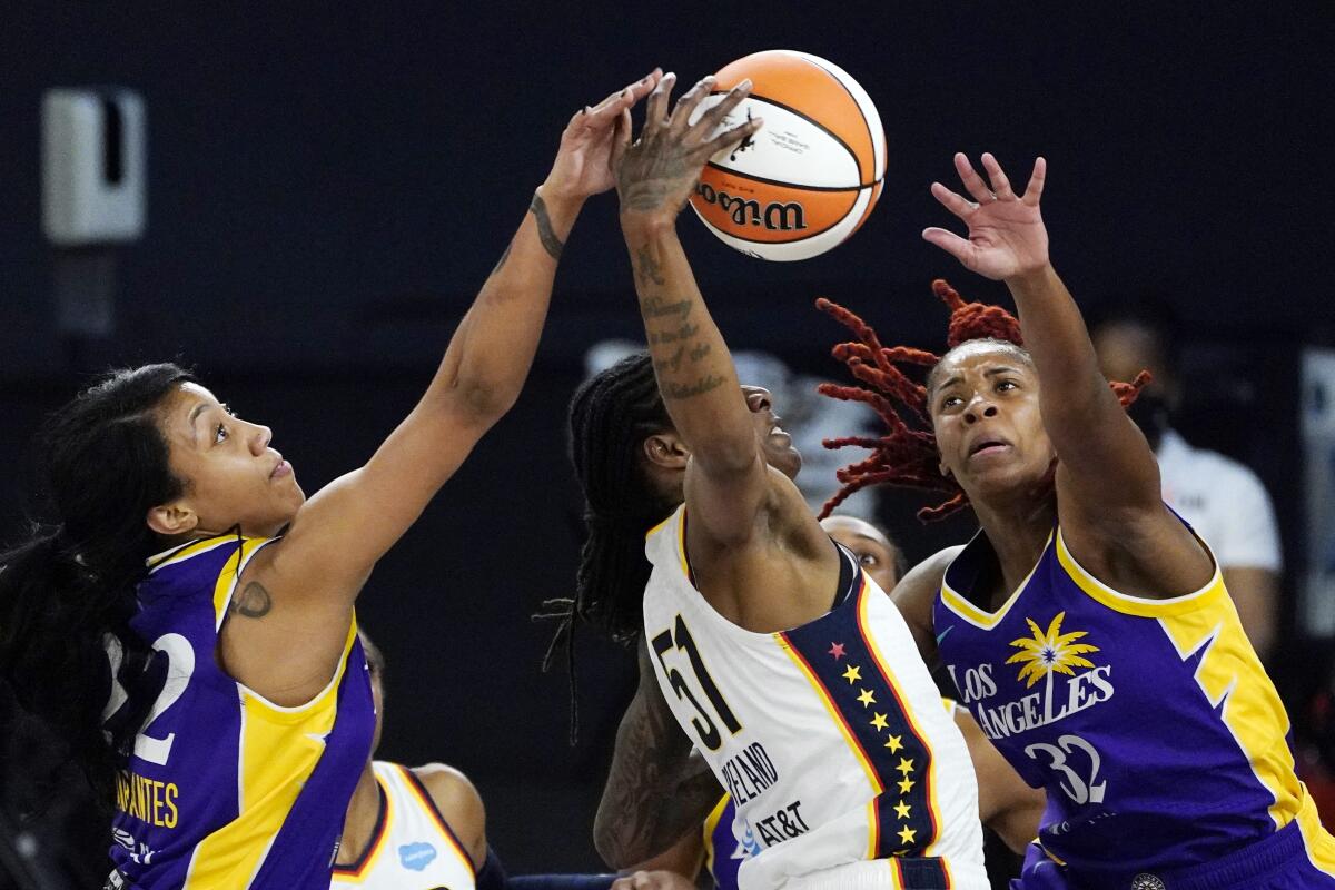 Indiana Fever's Jessica Breland reaches for a rebound along with Sparks guards Arella Guirantes and Bria Holmes.