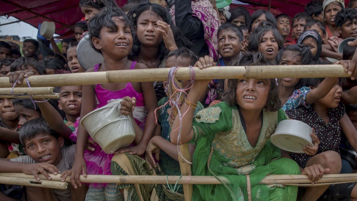 In this file photo, Rohingya Muslim children wait for food handouts distributed by a Turkish aid agency at the Thaingkhali refugee camp in Bangladesh.