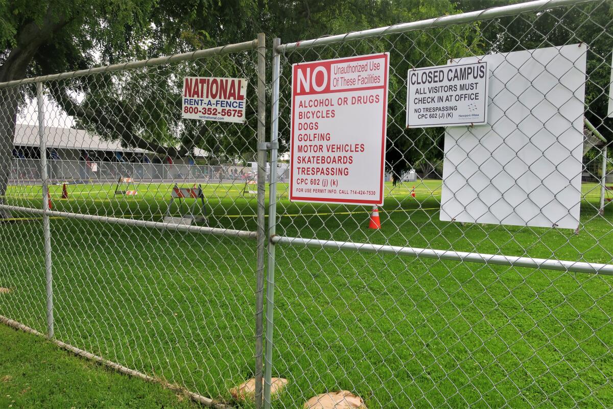 Signs on a chain-link fence installed at Costa Mesa's Harper Park this summer warn against trespassing.