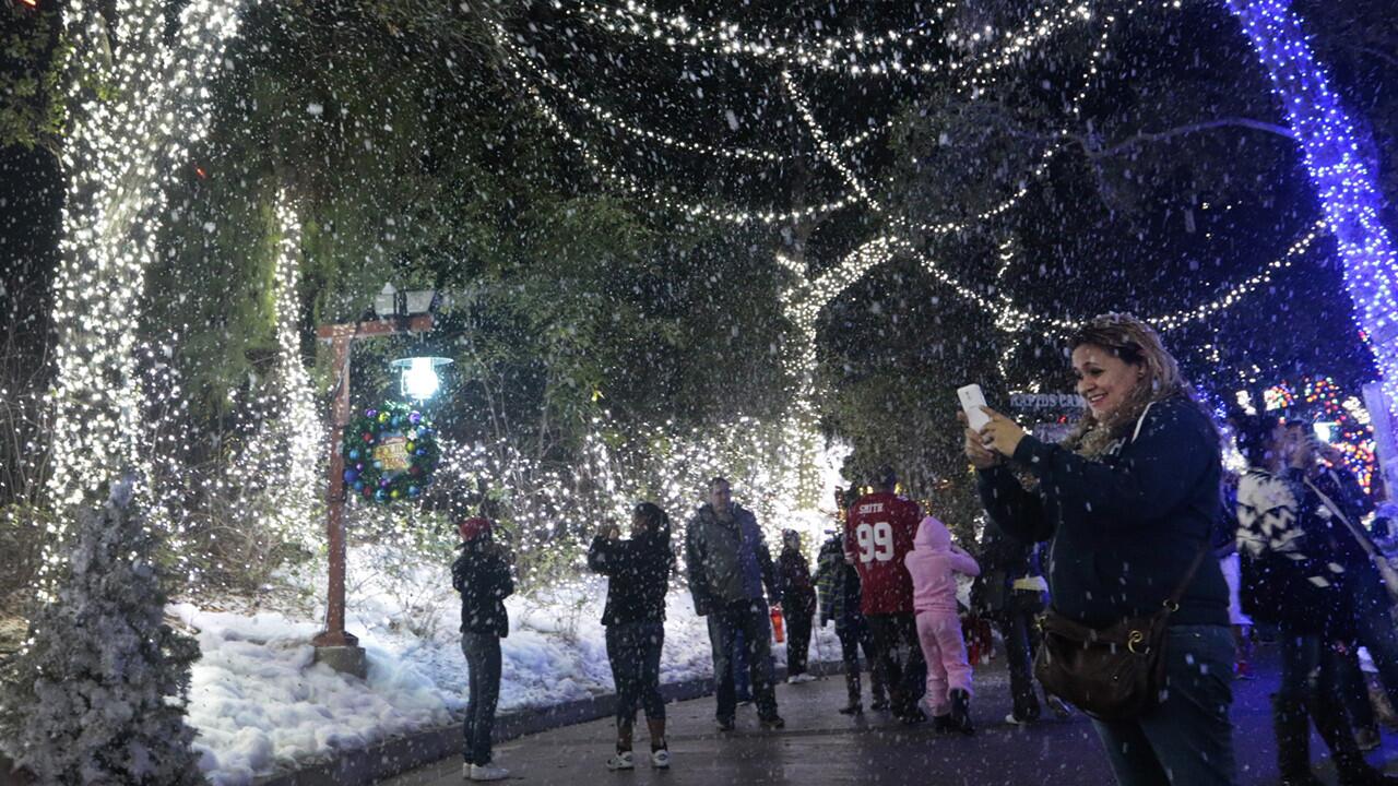 Park visitors take photos of snow scenes at Six Flags Magic Mountain in Valencia. The theme park this year added light shows, live music, carolers and new food items as part of a "Holiday in the Park" promotion.