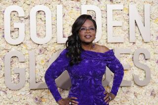 Oprah Winfrey poses in purple cowl neck gown on the 2024 Golden Globes carpet 