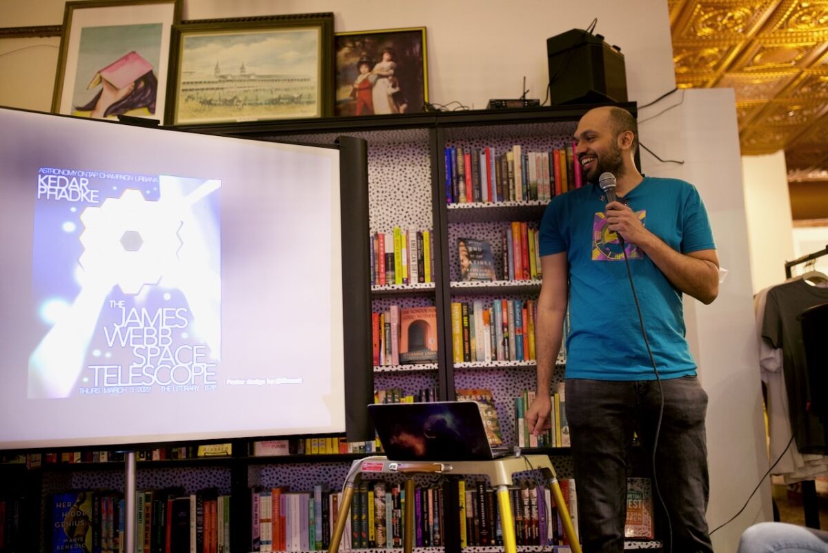 Kedar Phadke speaks into a microphone as he looks at a screen with an image