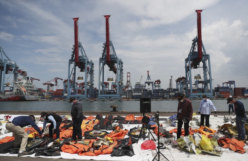 Investigators from Indonesian National Transportation Safety Committee (KNKT) and U.S. National Transportation Safety Board (NTSB) inspect debris found in the waters around the location where a Sriwijaya Air passenger jet crashed, at the search and rescue command center at Tanjung Priok Port in Jakarta, Indonesia Saturday, Jan. 16, 2021. (AP Photo/Achmad Ibrahim)