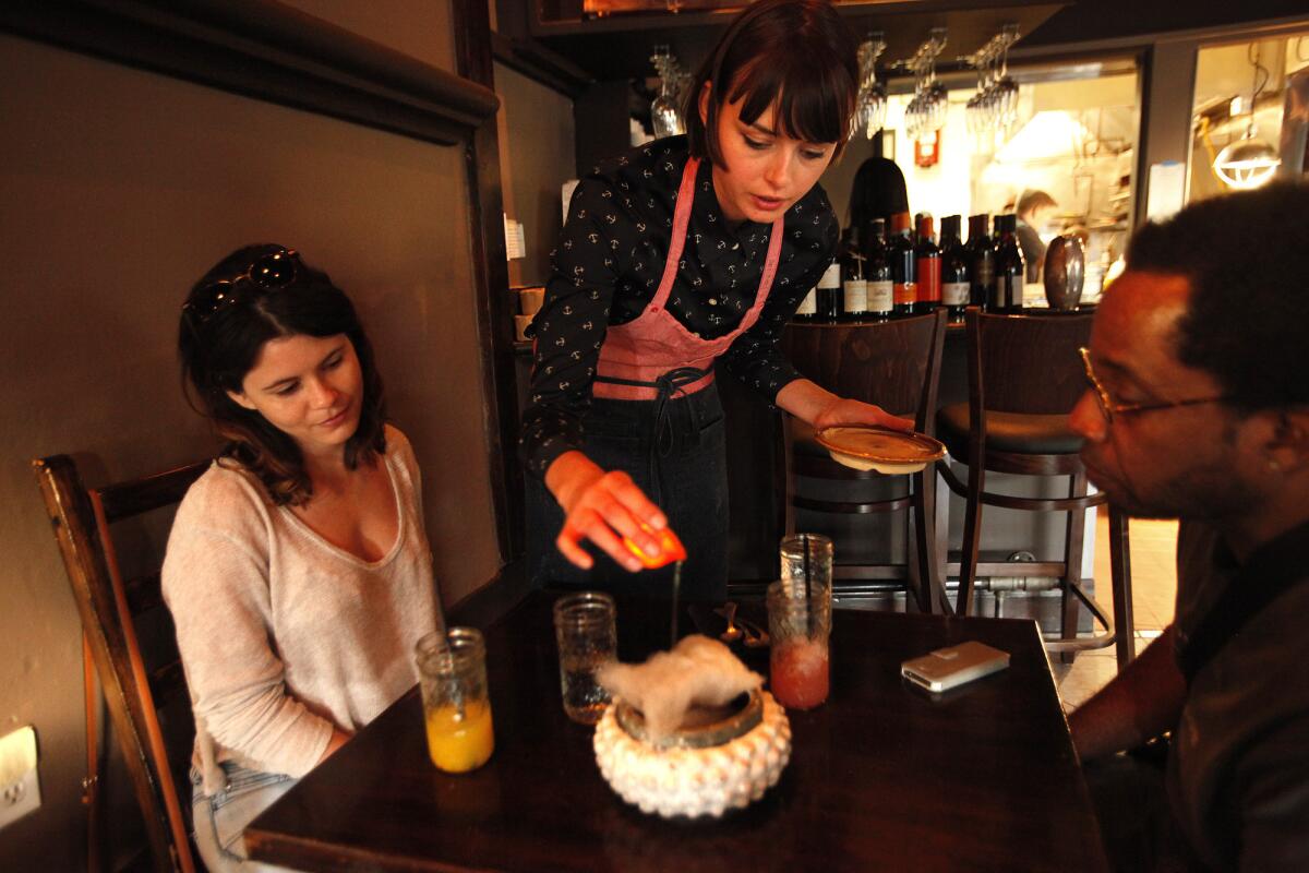 Margarita Lee pours hot olive oil, from a candle made from an orange, over a dessert at the Gadarene Swine.