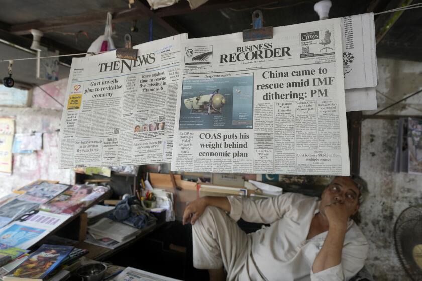 A vendor sits beside a copy of a morning newspaper which reports missing Titanic submersible and onboard five people, including Pakistani nationals Shahzada Dawood and his son Suleman, at a stall, in Karachi, Pakistan, Wednesday, June 21, 2023. A Canadian military surveillance aircraft detected underwater noises as a massive operation searched early Wednesday in a remote part of the North Atlantic for a submersible that vanished while taking five people down including Dawood, a well-known Pakistani businessman and his 19-year-old son to the wreck of the Titanic. (AP Photo/Fareed Khan)