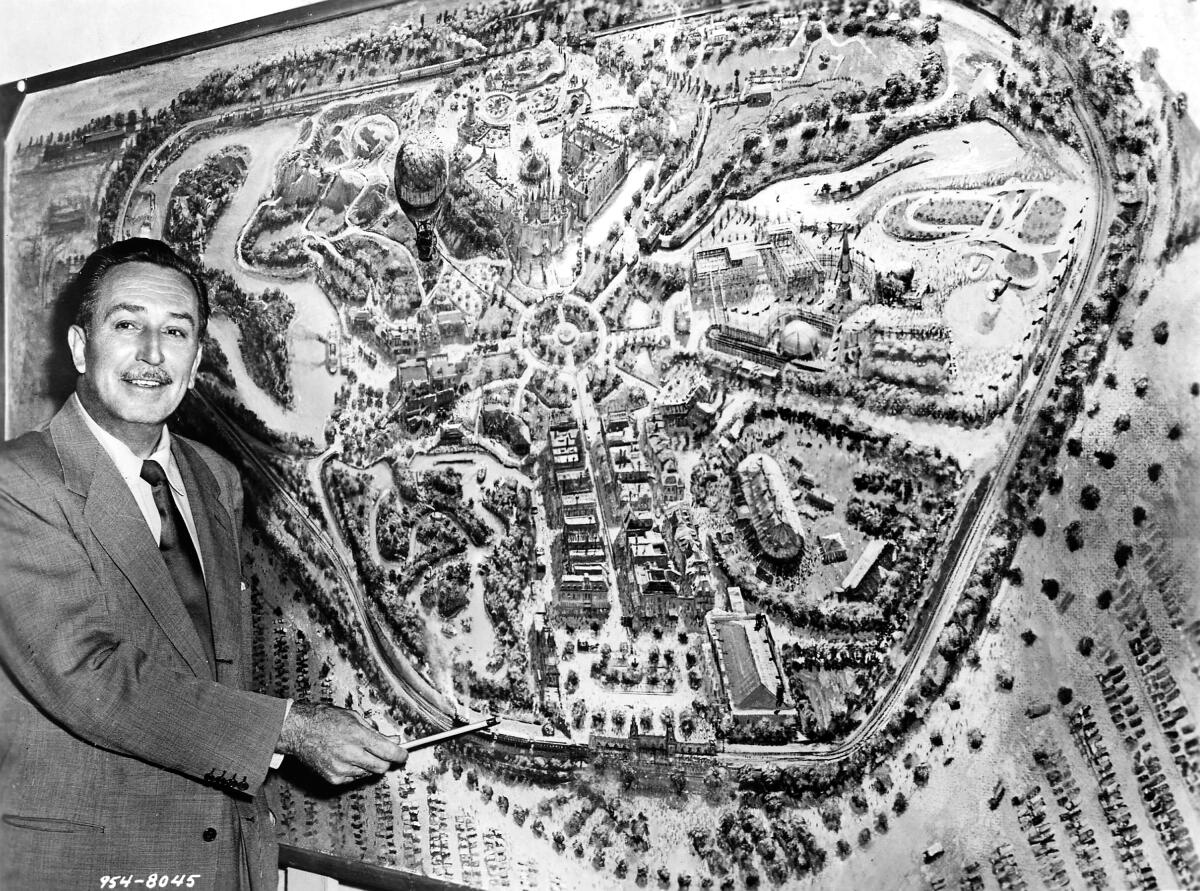 Walt Disney points at a map of Disneyland. 1955 photo, credited to Disneyland.