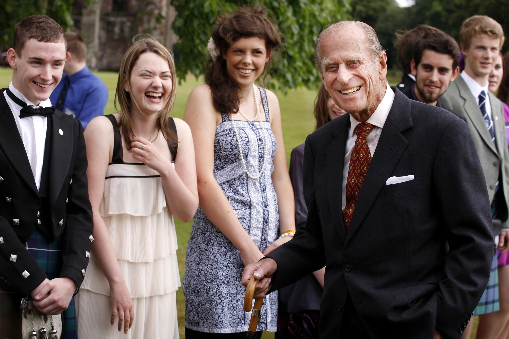 Prince Philip smiles as a line of young people burst into laughter