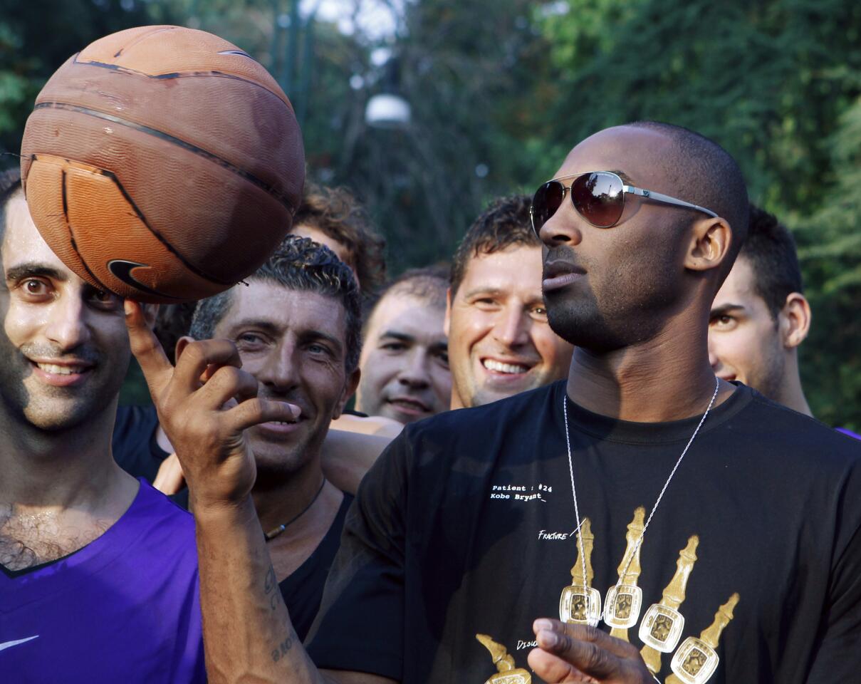 Kobe Bryant balances a basketball on his finger for a crowd in Milan, Italy, in 2011.