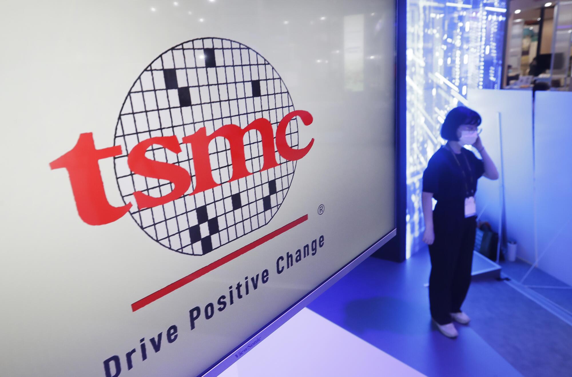 The TSMC (Taiwan Semiconductor Manufacturing Co.) logo next to a woman wearing a mask.