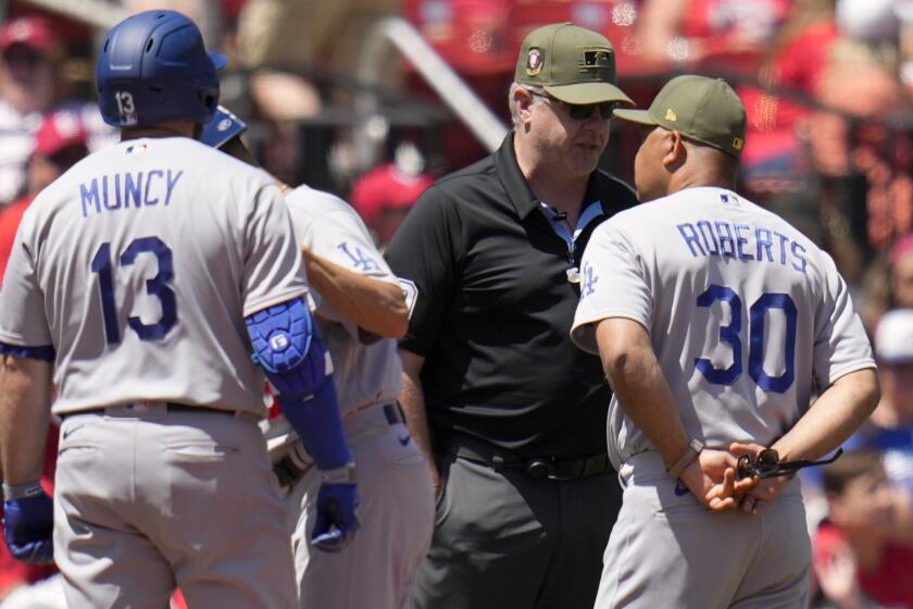 Los Angeles Dodgers manager Dave Roberts (30) talks with third base umpire Paul Emmel.