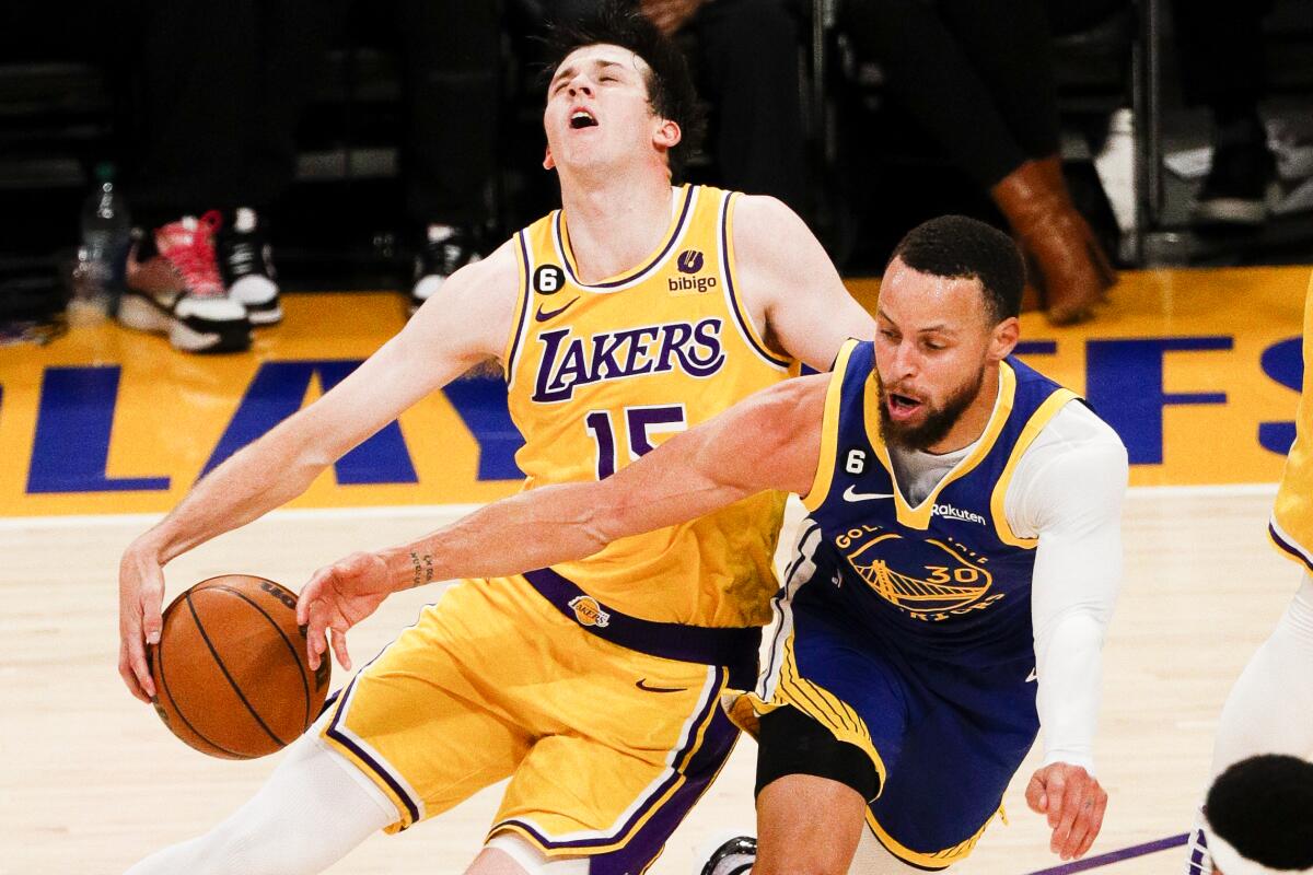 The Warriors' Stephen Curry, right, bumps into Lakers guard Austin Reaves while trying to steal the ball.
