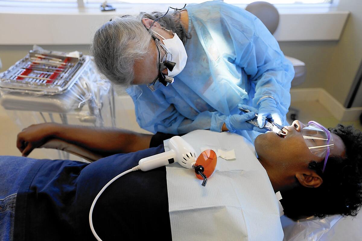 Dental hygienist Margaret Newville works on patient Nuwan Karunaratne during a training program at West Coast University in Anaheim. A new state law authorizes hygienists to treat cavities without a dentist on site by placing low-cost, temporary fillings.