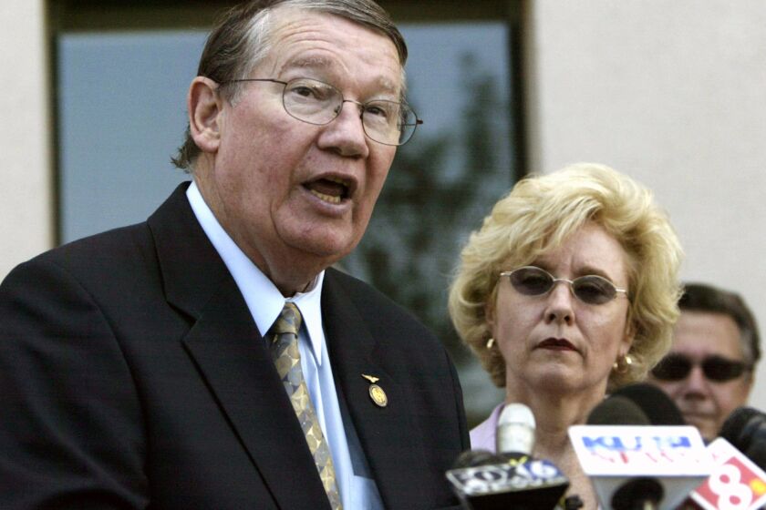 File-This July 2005 file photo shows former Republican U.S. Rep. Randy "Duke" Cunningham, flanked by his wife Nancy, during a news conference in San Marcos, Calif. Cunningham, whose feats as a Navy flying ace during the Vietnam War catapulted him to a U.S House career that ended in disgrace when he was convicted of accepting $2.4 million in bribes from defense contractors, is completing one of the longest prison sentence ever given to a member of Congress. Cunningham, 71, is due to be released Tuesday June 4, 2013. (AP Photo/Lenny Ignelzi,File)