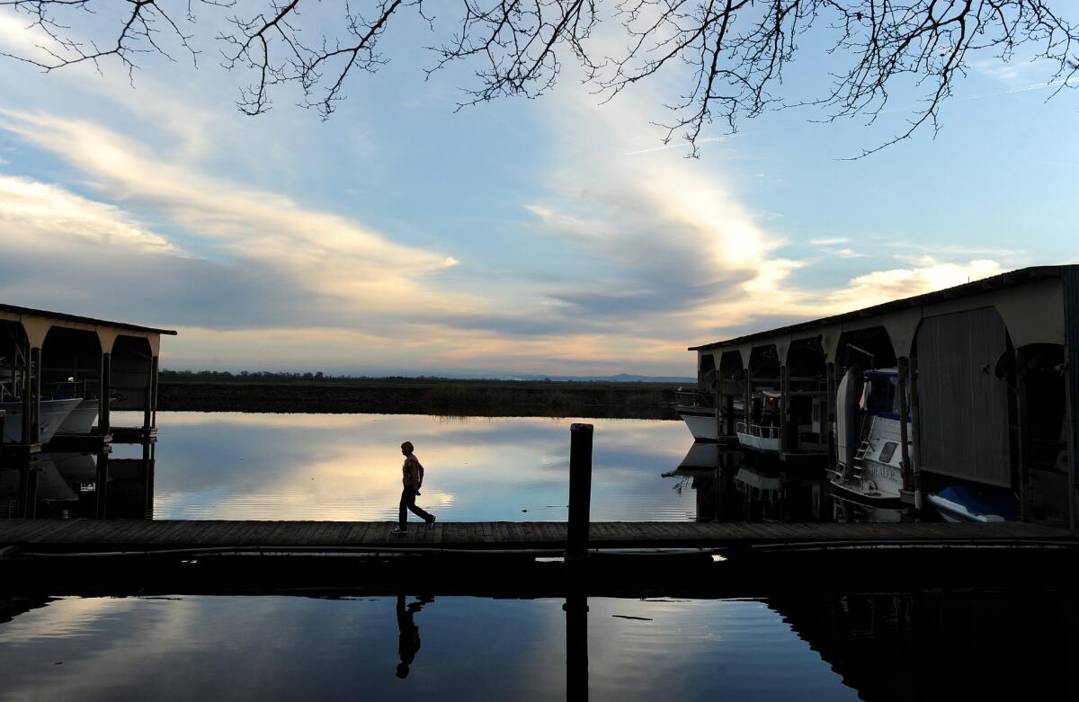A woman walks on the dock at the Tower Park Resort & Marina in the Sacramento-San Joaquin River Delta. Lawmakers have approved a bill that would require a public vote before the state could build water tunnels under the delta.