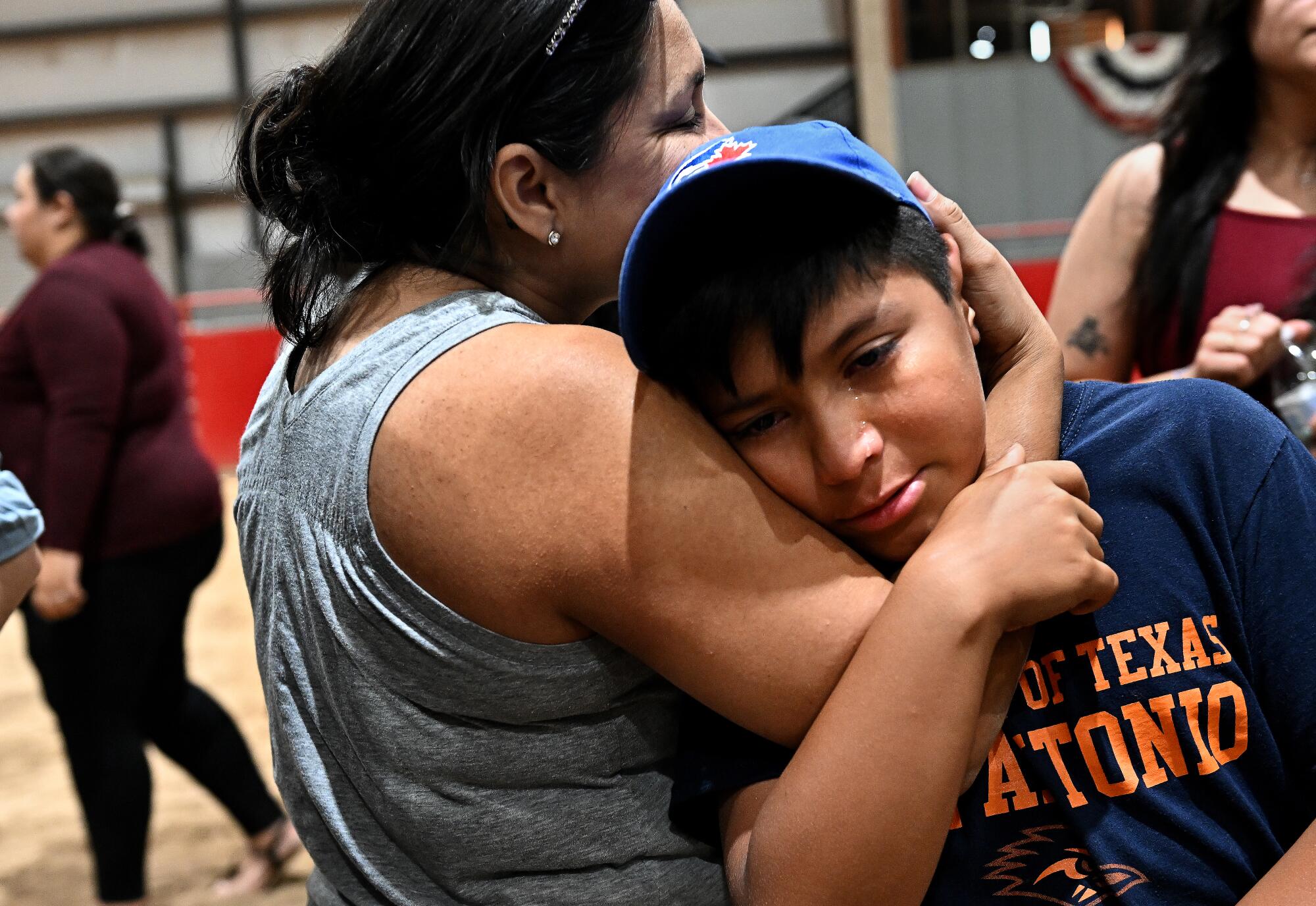 A woman holds a boy's head in the crook of her arm 