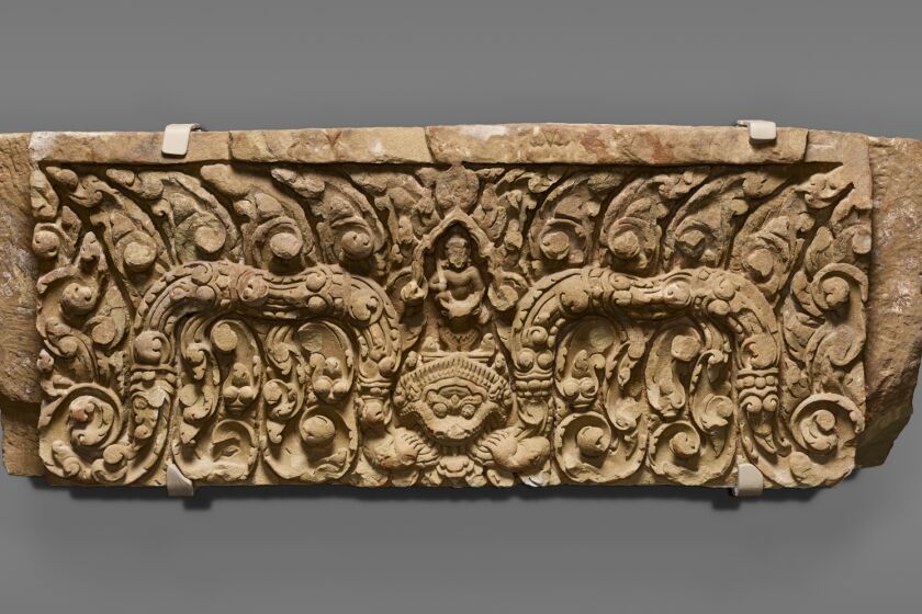 A stone carving in high relief shows Yama on a buffalo over a Kala face with two garlands coming out of the mouth.