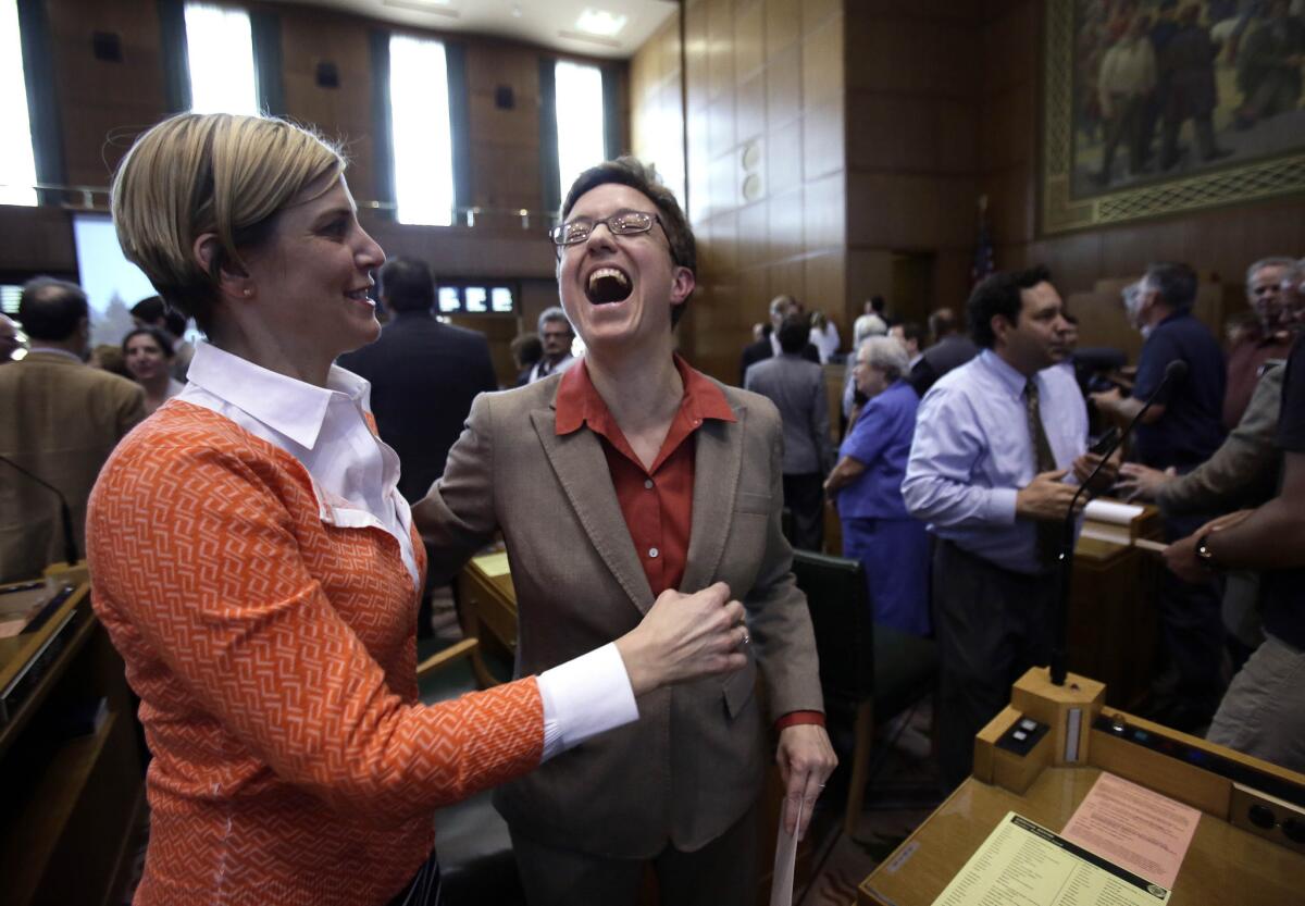 A new law in Oregon eliminates tax exemptions for charities that spend more than 70% of its funding on management and fundraising. Above: Oregon Speaker of the House Tina Kotek, right, shares a laugh on the House floor with Rep. Jennifer Williamson after the legislature adjourned in Salem.