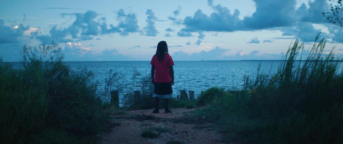 A man looks out over the water from the Alabama shoreline in a scene from the documentary "Descendant."