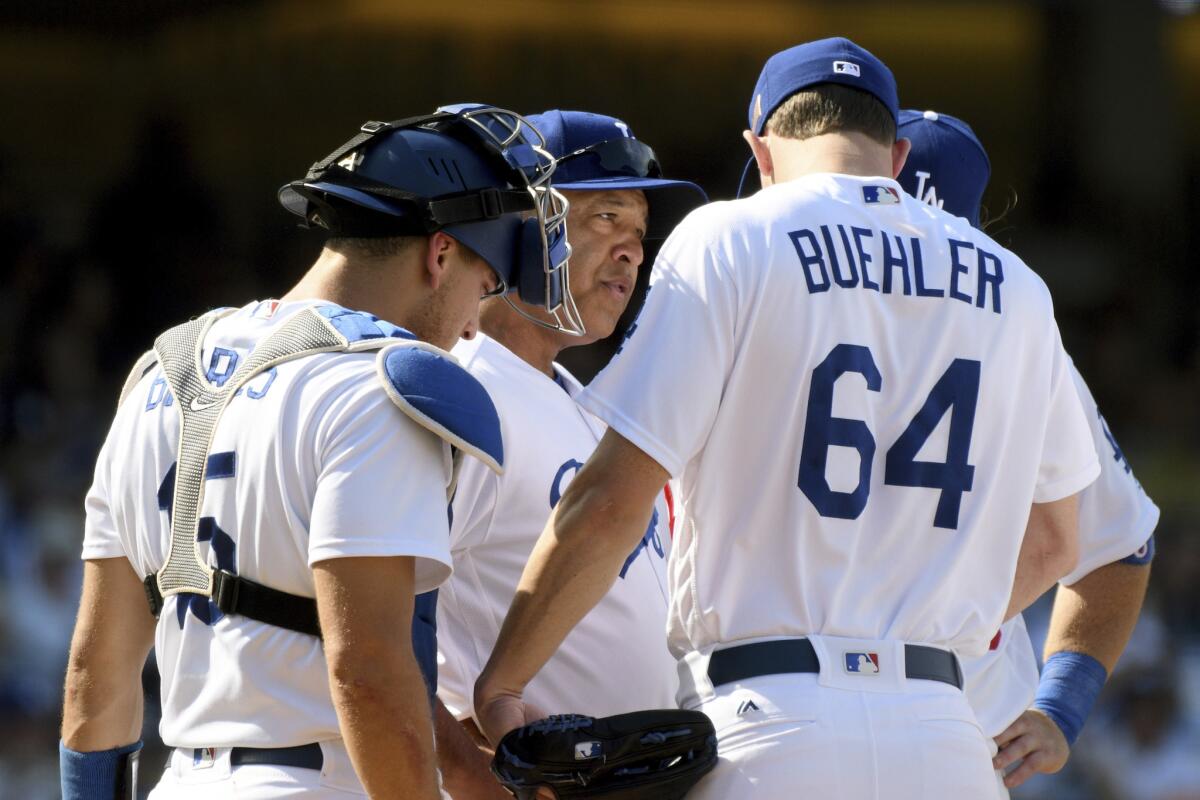 Los Angeles Dodgers manager Dave Roberts, second from left, talks with pitcher Walker Buehler (64) during a bases-loaded jam in the eighth inning of a baseball game against the Colorado Rockies, Sunday, Sept. 10, 2017, in Los Angeles.