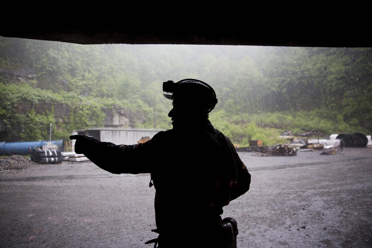 FILE - Coal miner Scott Tiller takes shelter from the rain after coming out of an underground mine at the end of a shift in Welch, W.Va., May 12, 2016. The sprawling economic package passed by the U.S. Senate this week has a certain West Virginia flavor. The bill could be read largely as an effort to help West Virginia look to the future without turning away entirely from its roots. (AP Photo/David Goldman, File)