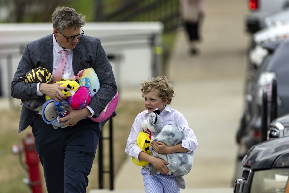 A man and young boy carrying several plush toys leave the funeral service held for The Covenant School shooting victim Evelyn Dieckhaus at the Woodmont Christian Church Friday, March 31, 2023, in Nashville, Tenn. The toys were donated by an anonymous donor for all the children in attendance. (AP Photo/Wade Payne)