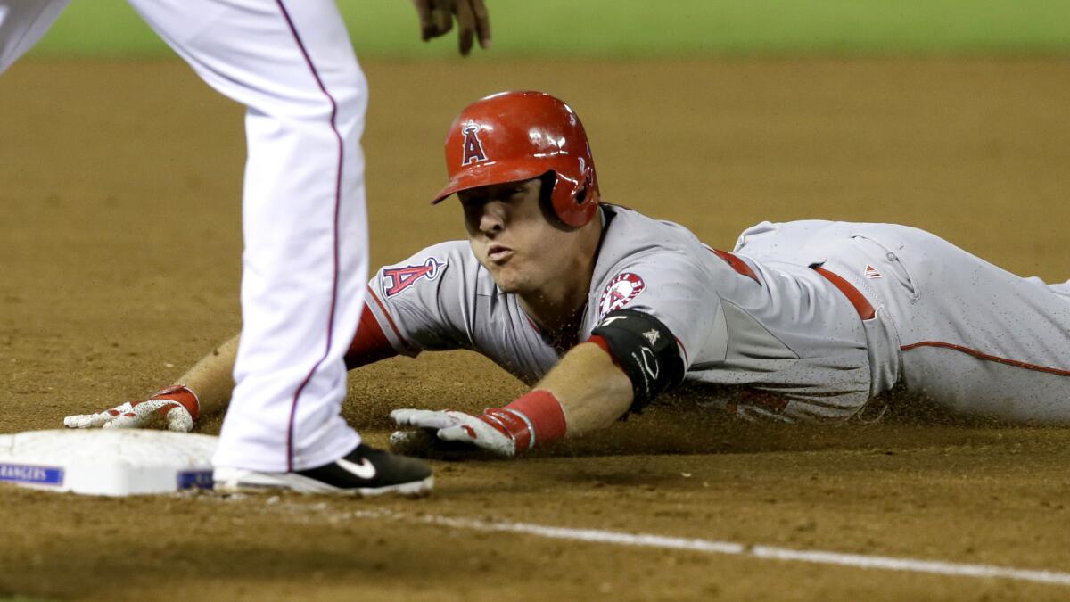 Angels center fielder Mike Trout slides into third base with a leadoff triple against the Rangers in the ninth inning Friday night in Arlington.