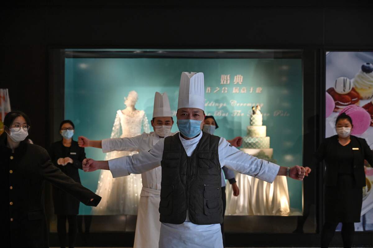 Wuhan hotel workers exercise in the lobby during a staff briefing about how to implement new health regulations.