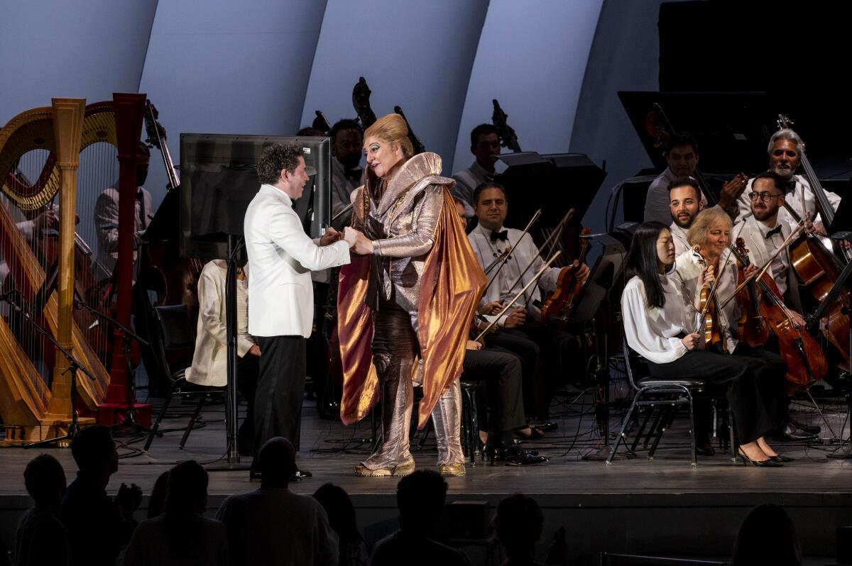 An actor in a space-age suit shakes hands with a conductor.