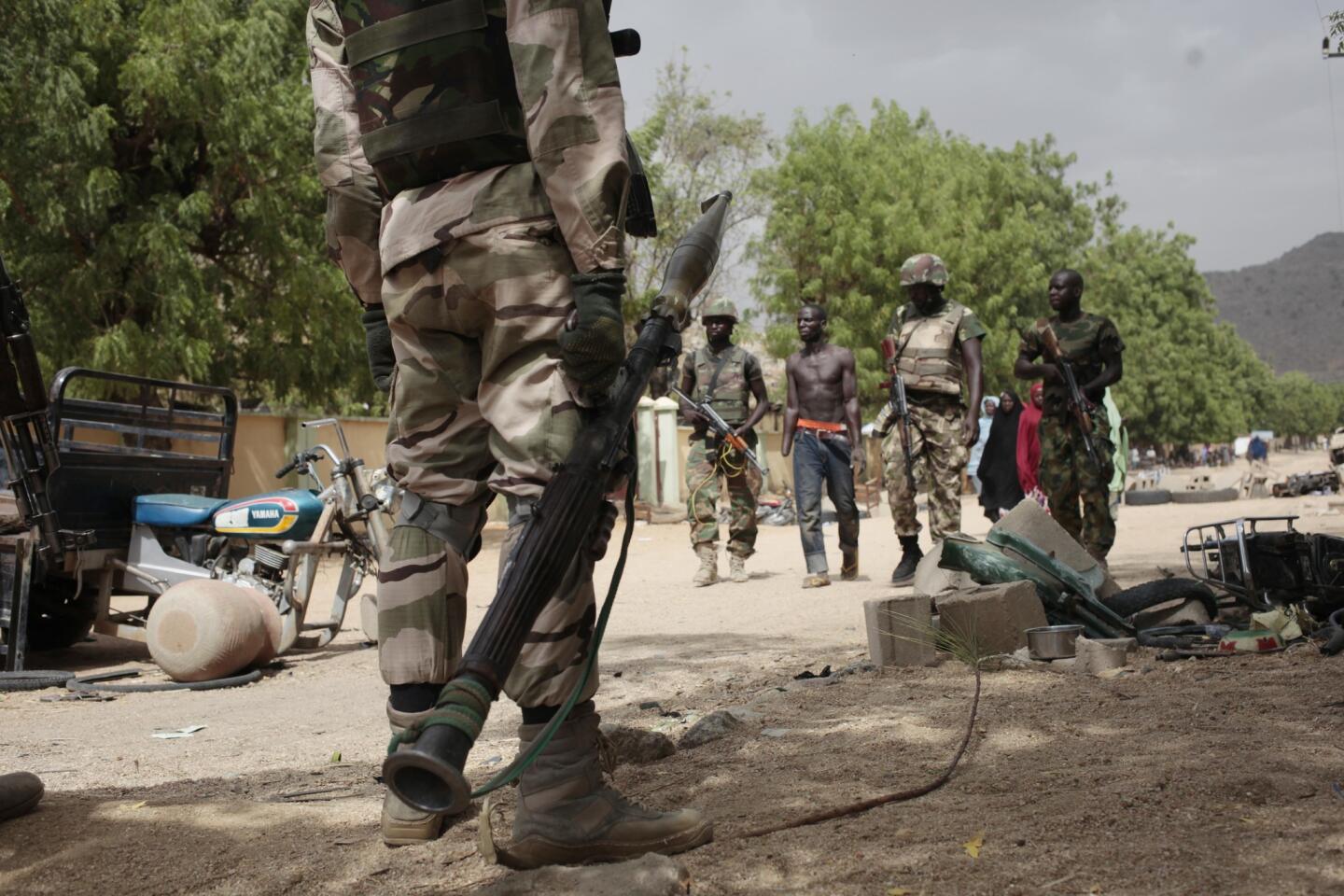 Nigerian soldiers in Gwoza escort Hassan Usman, who had been forced into labor by Boko Haram and had his hand amputated after the Islamic militants accused him of stealing fuel.
