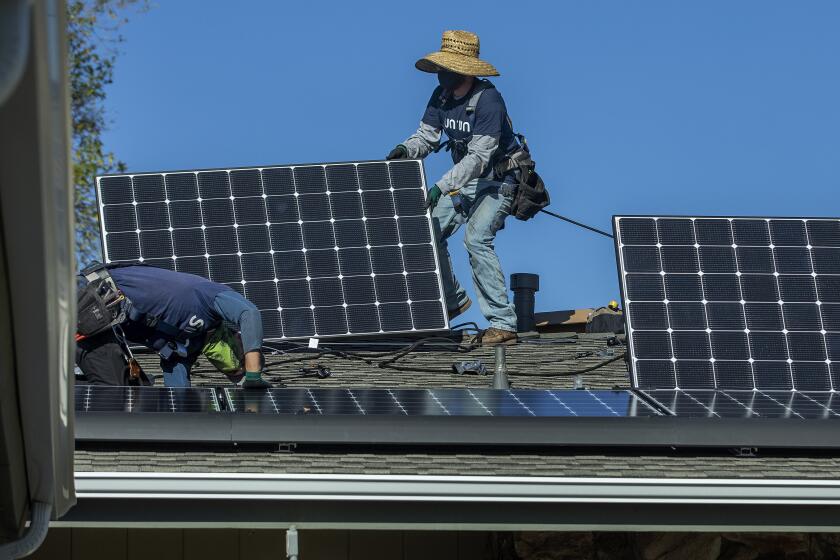 GRANADA HILLS, CA - JANUARY 04, 2020: Aaron Newsom, left, an installer for the solar company, Sunrun, and Tim McKibben, a senior installer, install solar panels on the roof of a home in Granada Hills. (Mel Melcon / Los Angeles Times)