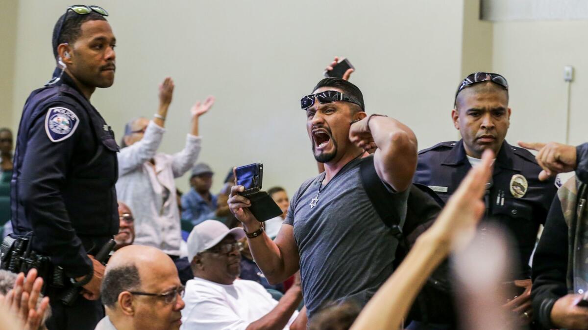 Harim Uzziel, center, a friend of Schaper's and fellow member of the L.A. County for Trump coalition, is escorted from a town hall meeting held by Rep. Maxine Waters in Inglewood in May. (Irfan Khan / Los Angeles Times)