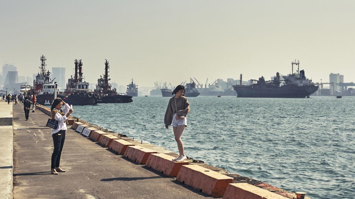 Kaohsiung has tried to rebrand itself as a tourist hub, with little success so far. Here, a few tourists take pictures in front of Kaohsiung port's industrial skyline.