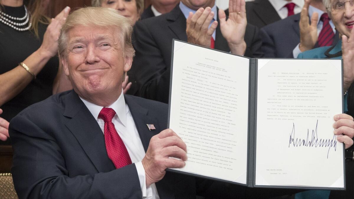 President Trump holds up an executive order on healthcare after signing it during a ceremony in the Roosevelt Room in October 2017.