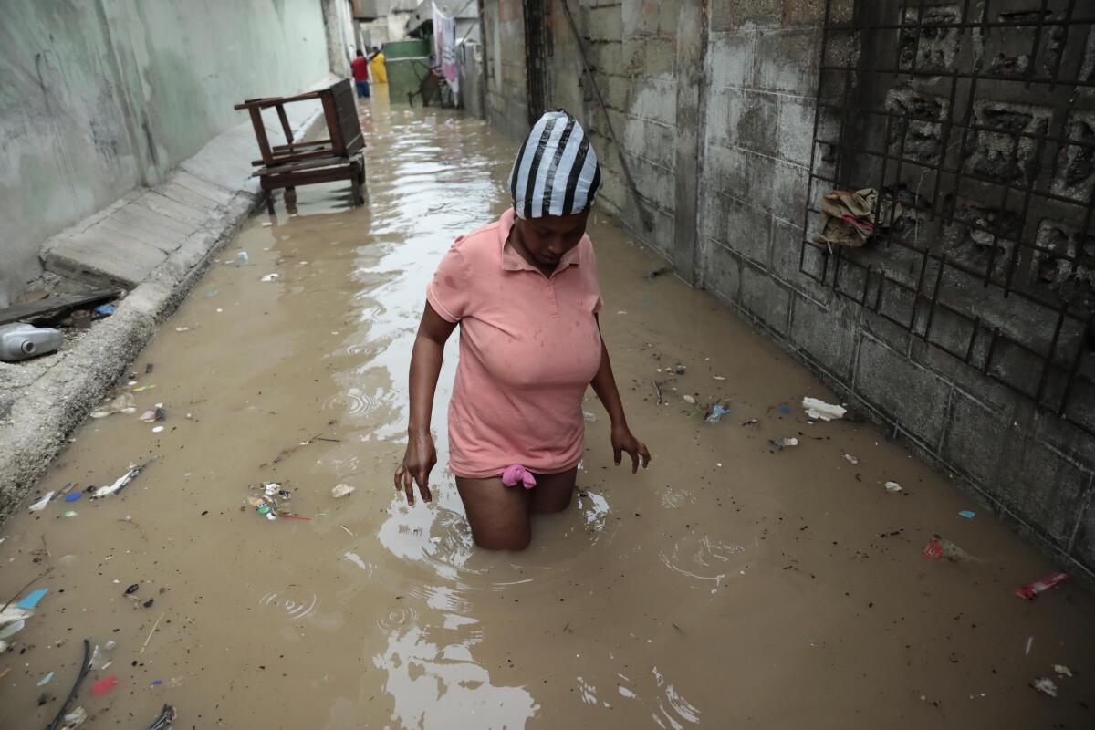 A woman walks through a flooded alleyway.