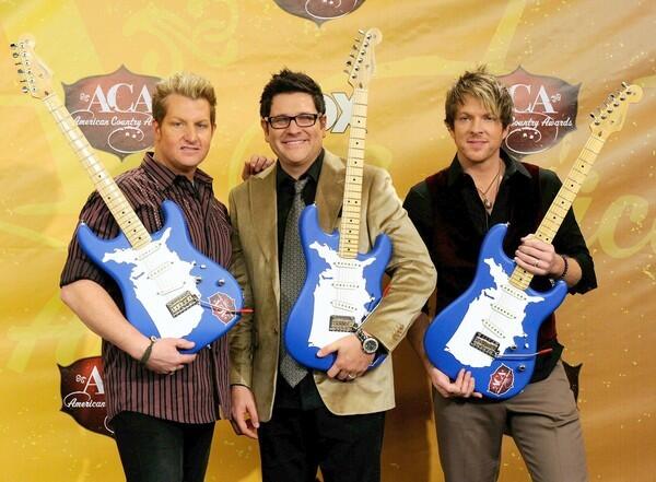 Gary LeVox, Jay DeMarcus and Joe Don Rooney of the band Rascal Flatts pose with guitar trophies after winning the Decade Award at the American Country Awards. The award signifies the band's contribution to country music over the last 10 years.